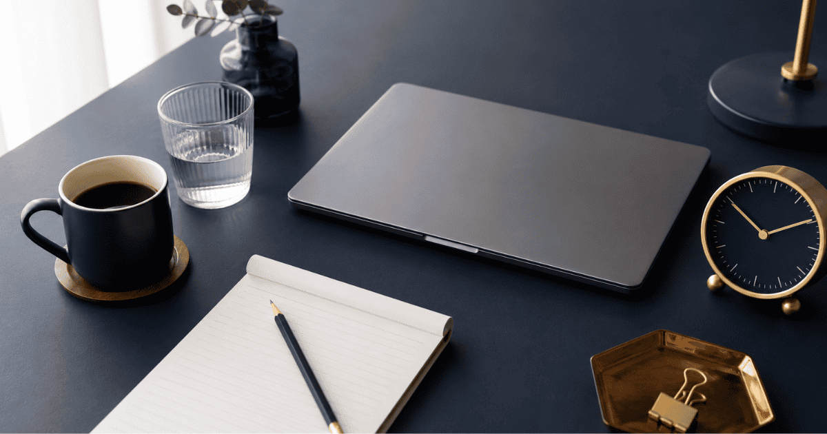 Focus productivity workspace with coffee, water and notepad arranged for a structured deep-work session